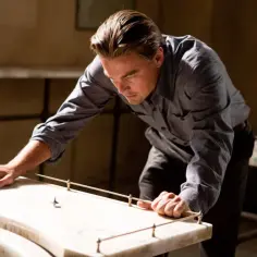 Leonardo DiCaprio pochyla się nad stołem, obserwując wirujący bączek. Czy to sen? Incepcja co to?
