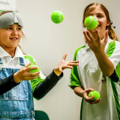 Dziewczynki żonglują piłeczkami, jedna z opaską na oczach. Czy to ćwiczenie na pamięć fotograficzną?